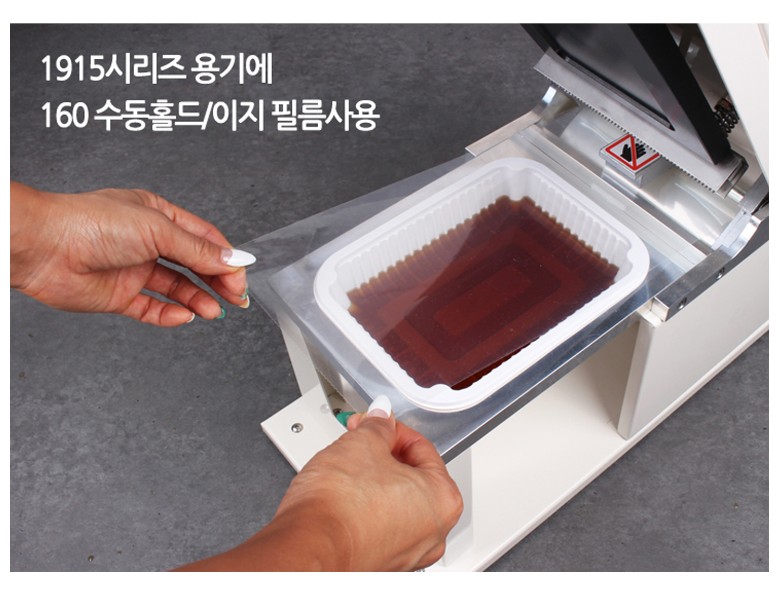 실링기계에 용기를 놓고, 수동홀드필름으로 실링하려는 이미지