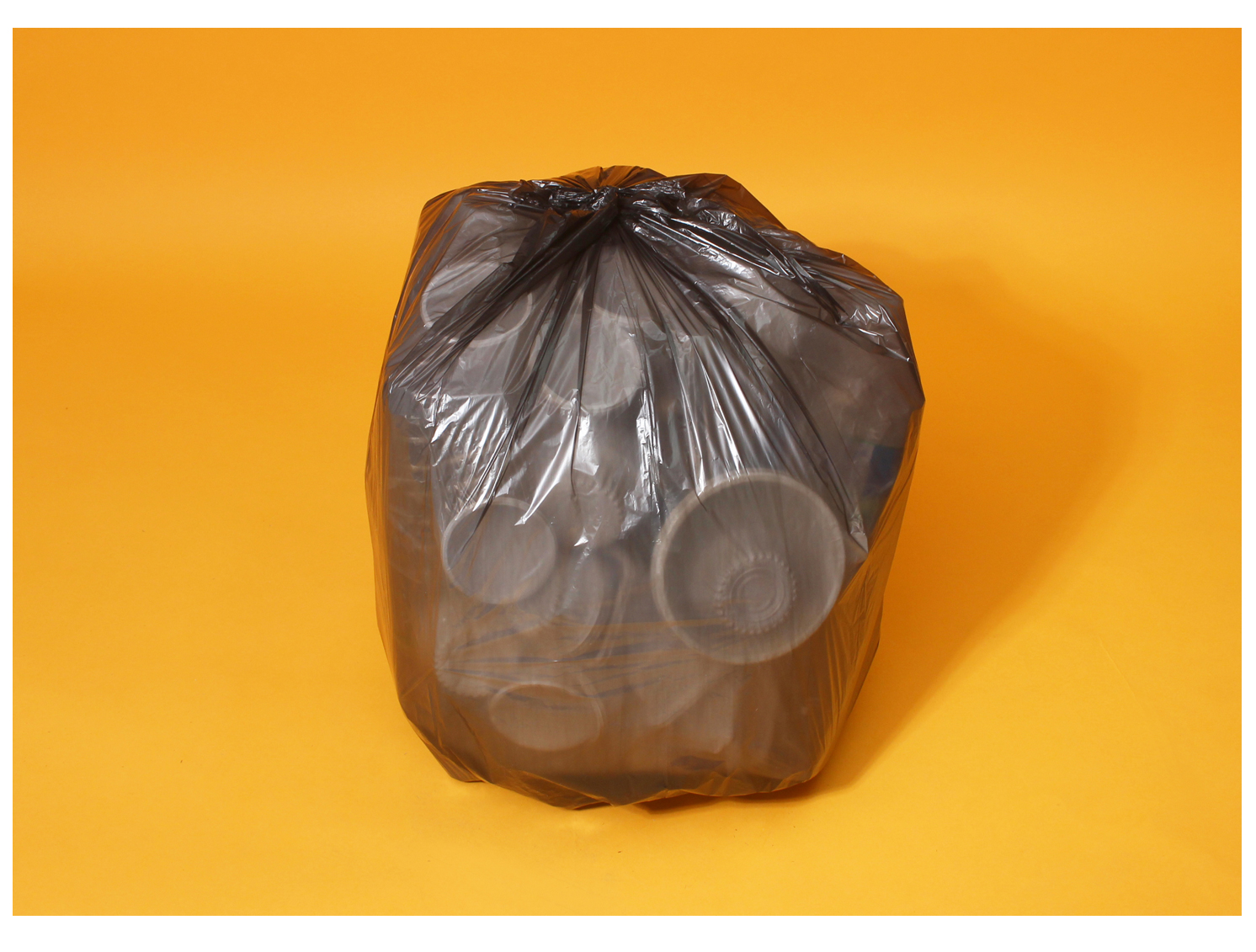 주황색 바탕화면에 쓰레기봉투에 재활용 플라스틱이 가득 담겨있다. 동그랗게 가득 묵여있는 모습이다.