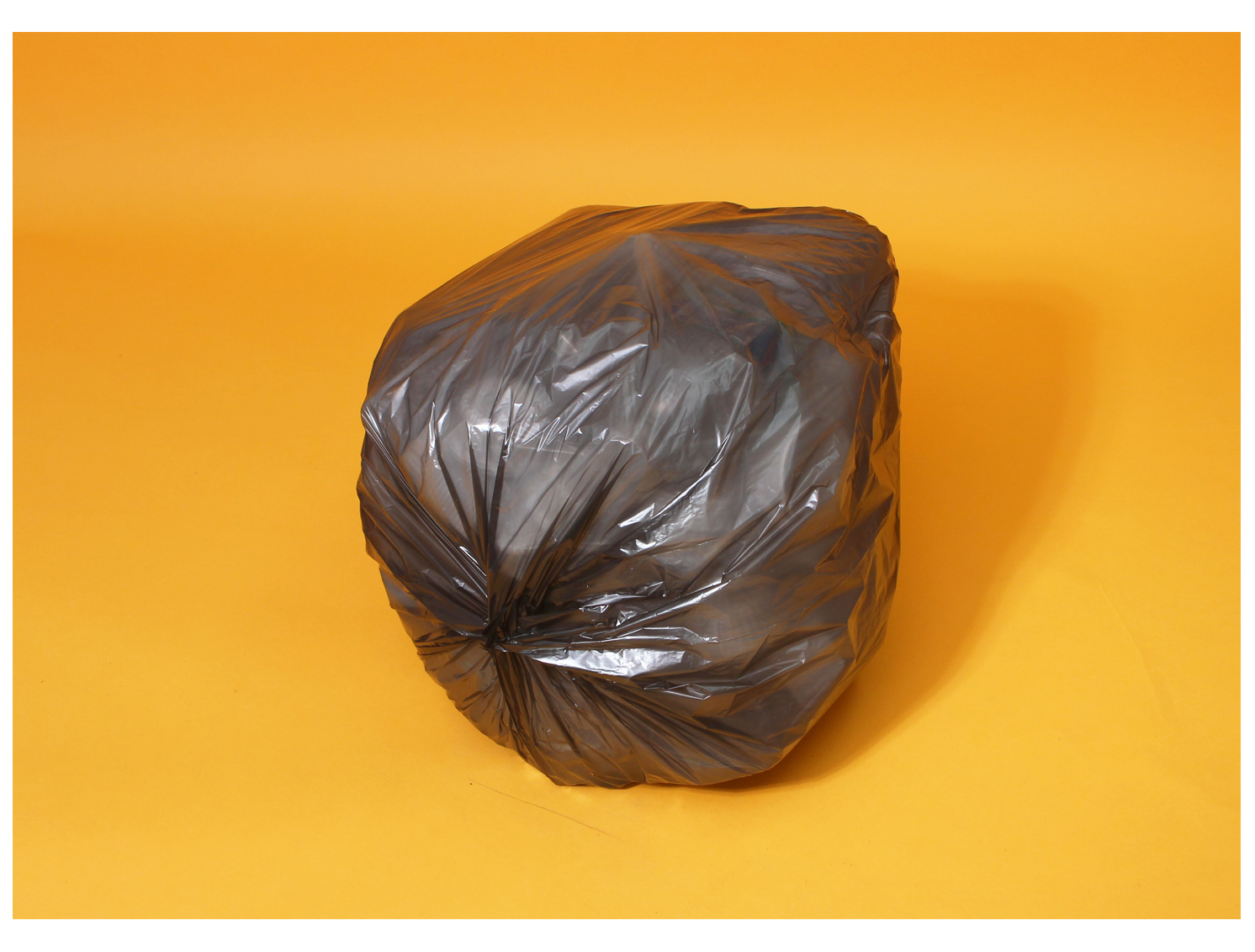 주황색 바탕화면에 쓰레기봉투에 재활용 플라스틱이 가득 담겨있다. 바닥면이 여러겹 배접 접합되어 동그랗게 모여있는 모습이다.