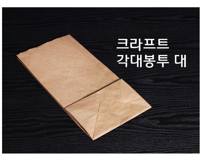 검정 배경에 얇게 접힌 상태의 크라프트 종이 각대봉투 하나가 놓여 있으며, 사용 전의 평평한 형태를 보여주는 구성.