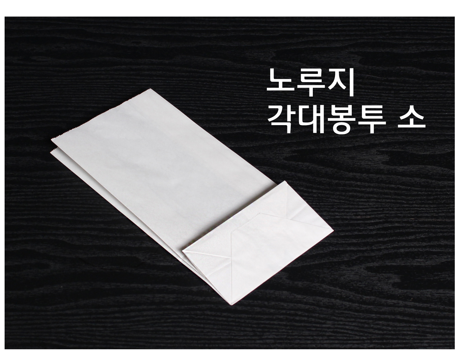 검정 배경에 얇게 접힌 상태의 노루지 종이 각대봉투 하나가 놓여 있으며, 사용 전의 평평한 형태를 보여주는 구성.